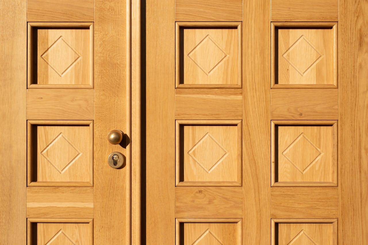 Close-up of a wooden door featuring geometric diamond patterns and a brass handle.