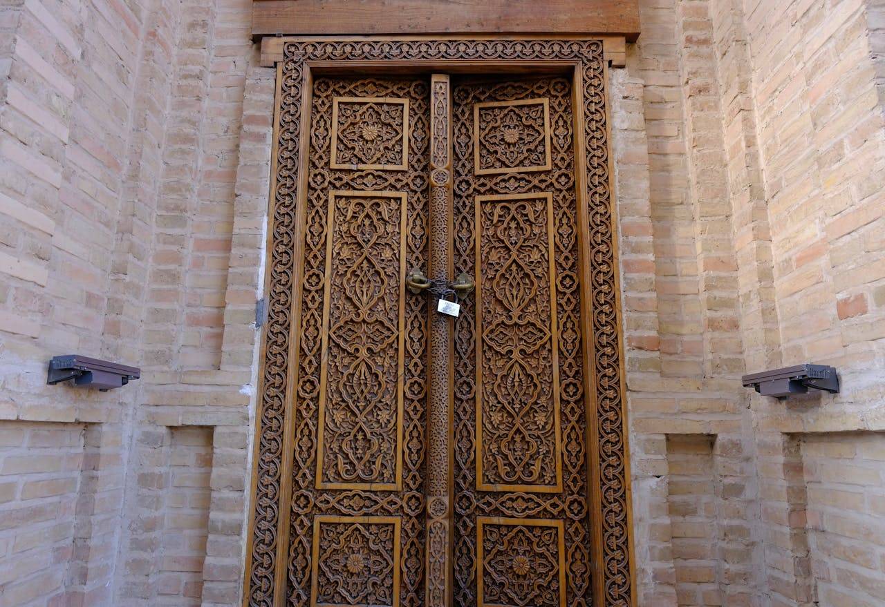 Beautiful carved wooden door with intricate patterns set in a brick wall.