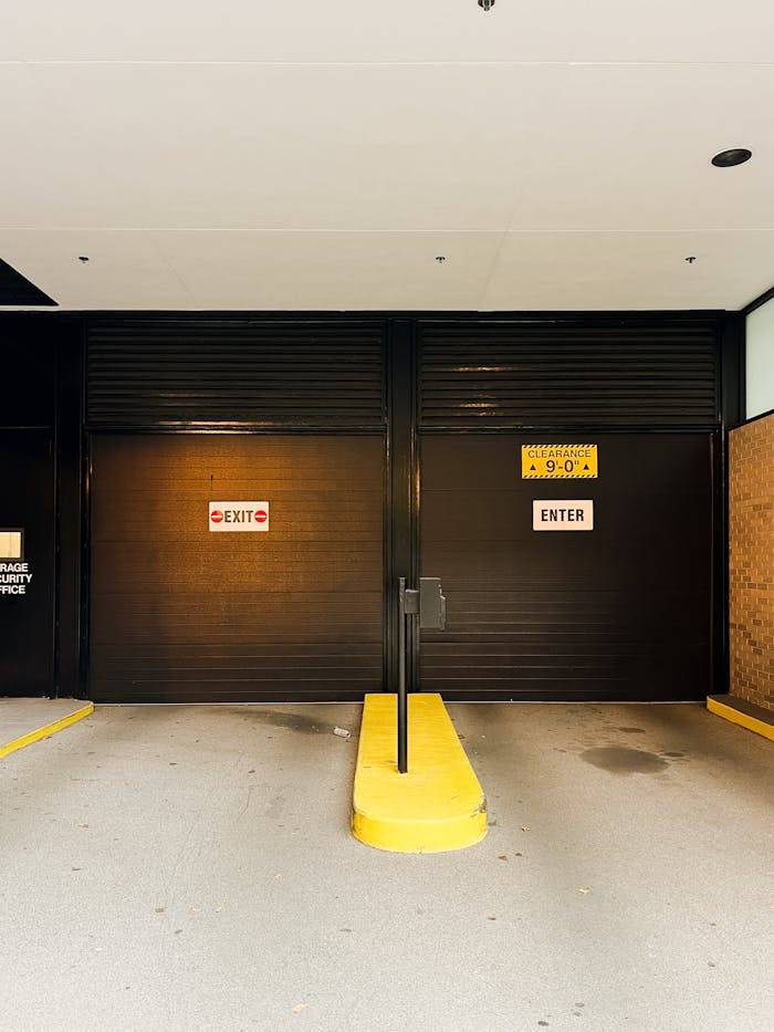 Photo of a garage entrance showing 'Exit' and 'Enter' signage with safety barriers.