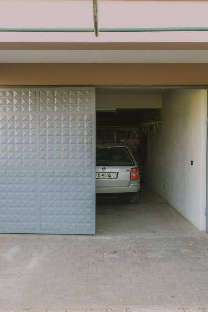 Partially open garage with parked car visible inside, featuring a modern sliding door design.