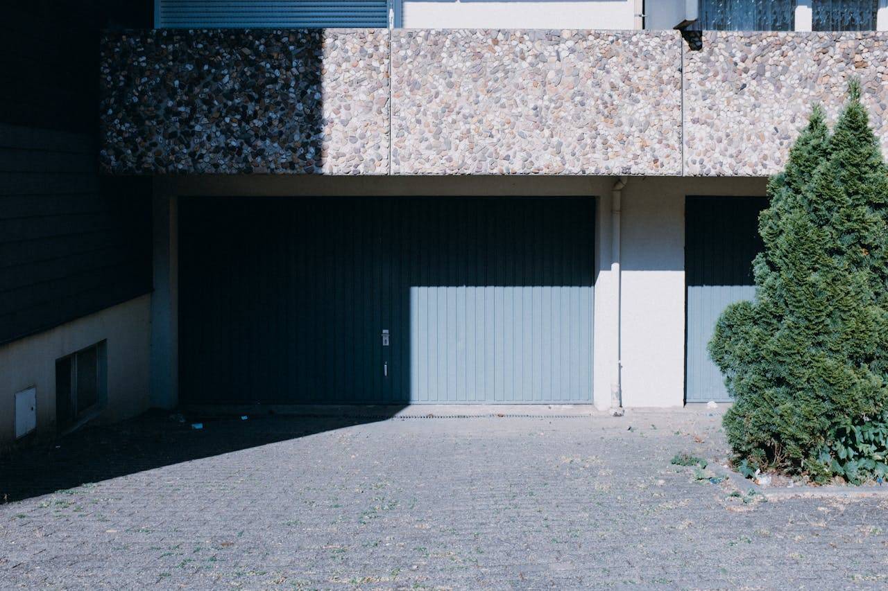 Contemporary house facade featuring dual garage doors and a lush green tree.