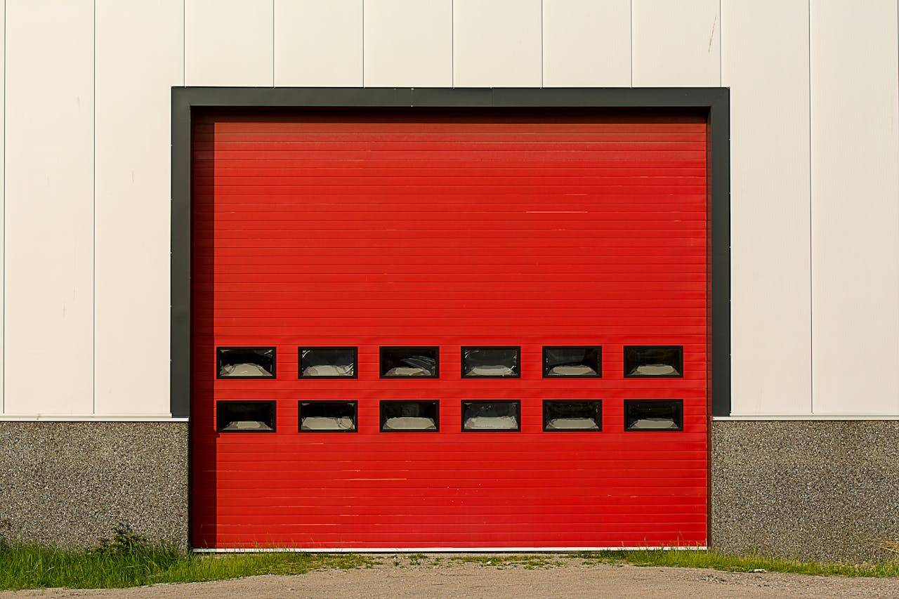 Bright red roller shutter garage door on industrial building exterior.