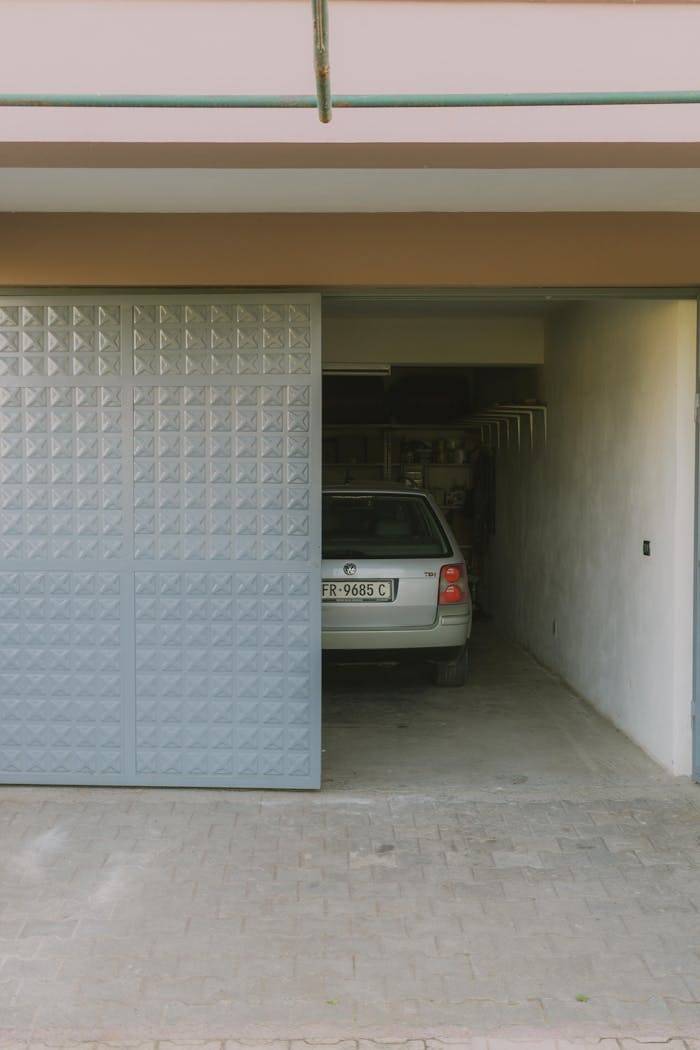 Partially open garage with parked car visible inside, featuring a modern sliding door design.