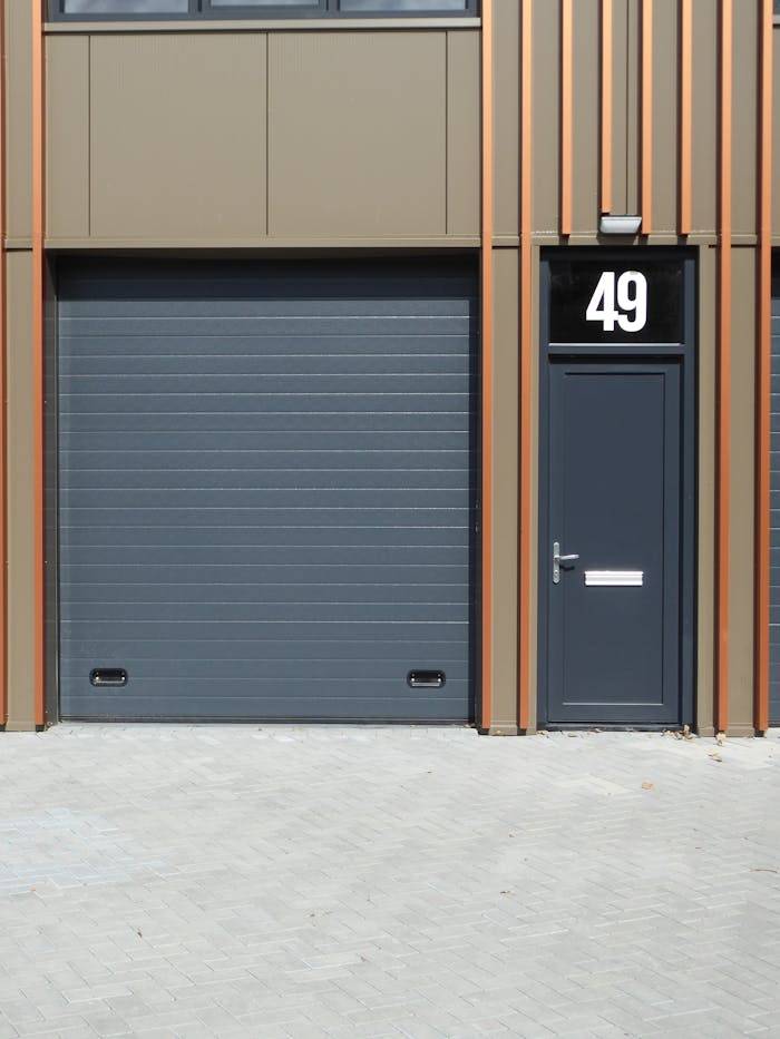 service-03 A contemporary building facade featuring a dark garage door and entrance with number 49.