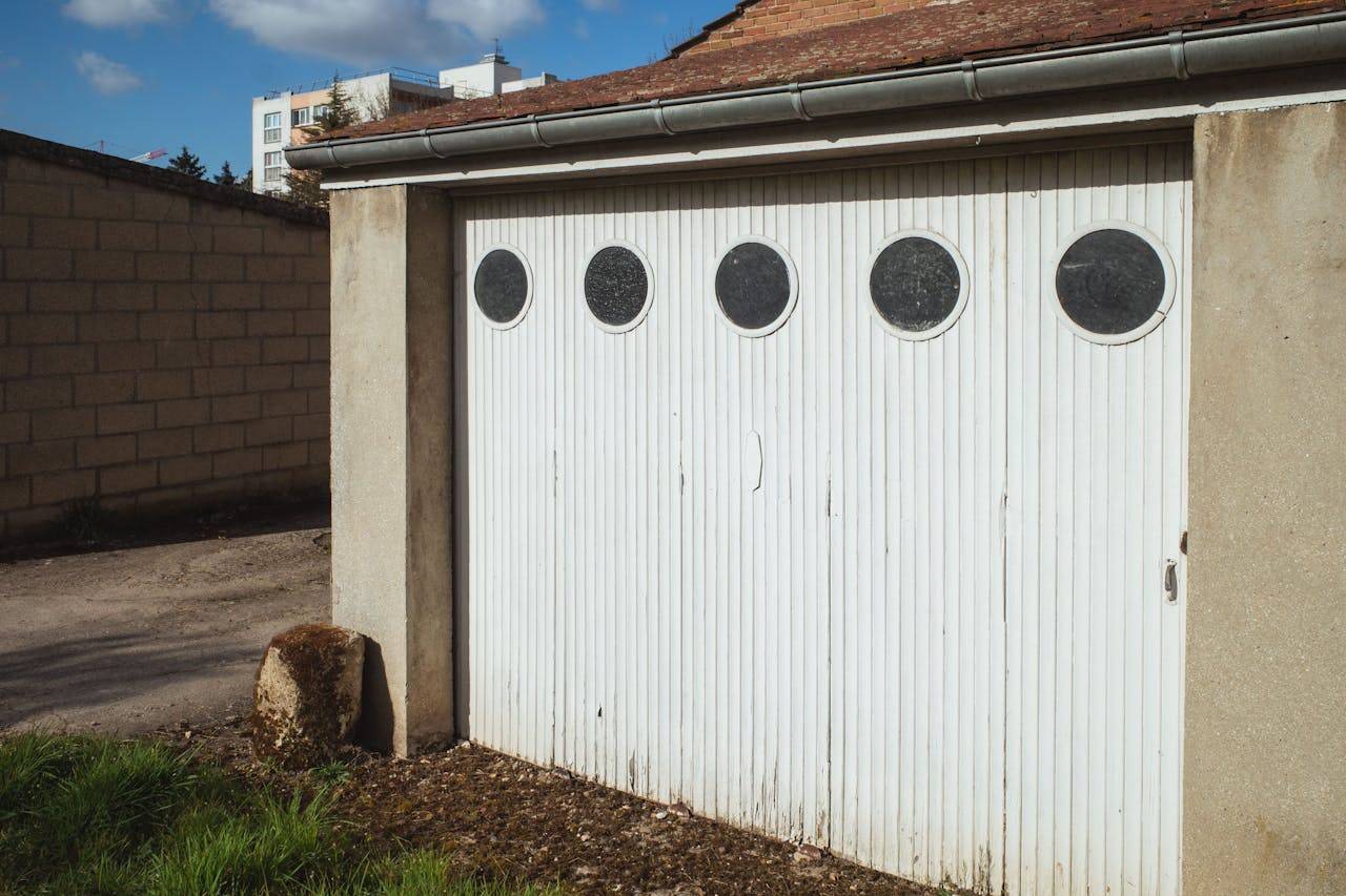 about-me-img White garage door with circular windows in a residential area of Compiègne, France.