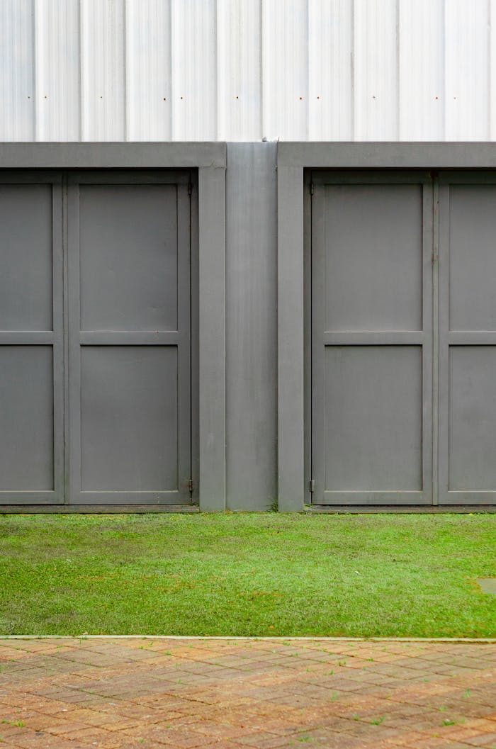 Close-up of two modern gray garage doors with grass and pavement.