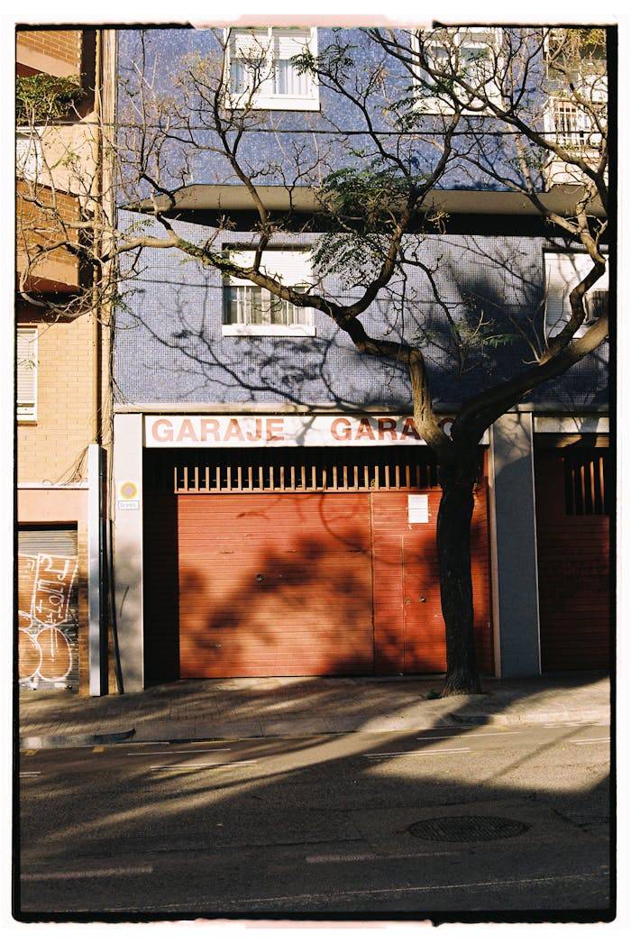 A city garage entrance with shadow patterns from a tree in sunlight.