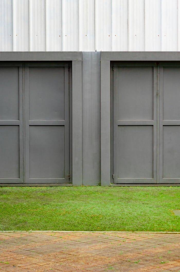 services-02 Close-up of two modern gray garage doors with grass and pavement.