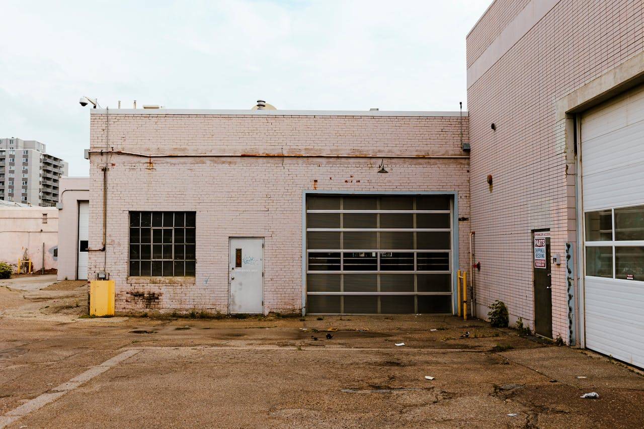 services-03 Industrial garage exterior showcasing urban decay with brick walls and graffiti.