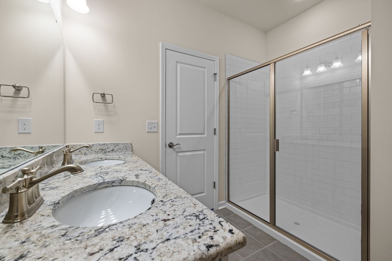 Elegant bathroom featuring granite countertops and a spacious glass shower enclosure.
