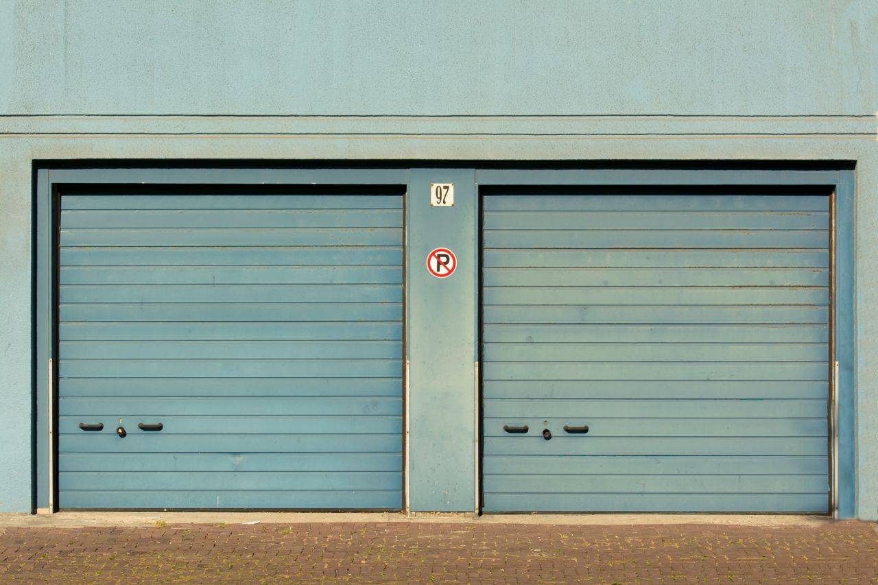 about-us-01 Blue garage doors with a no parking sign painted outdoors.