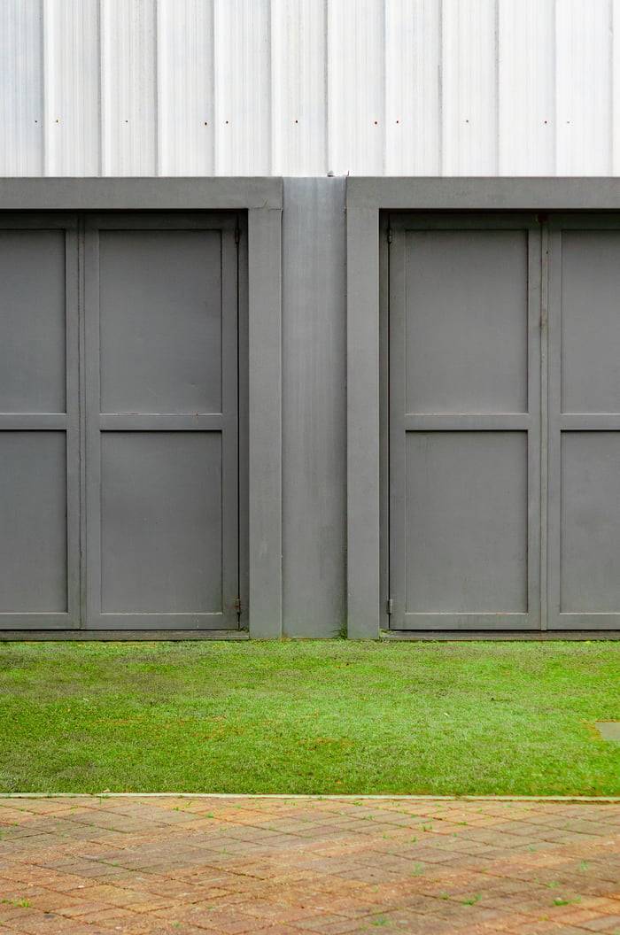 Close-up of two modern gray garage doors with grass and pavement.