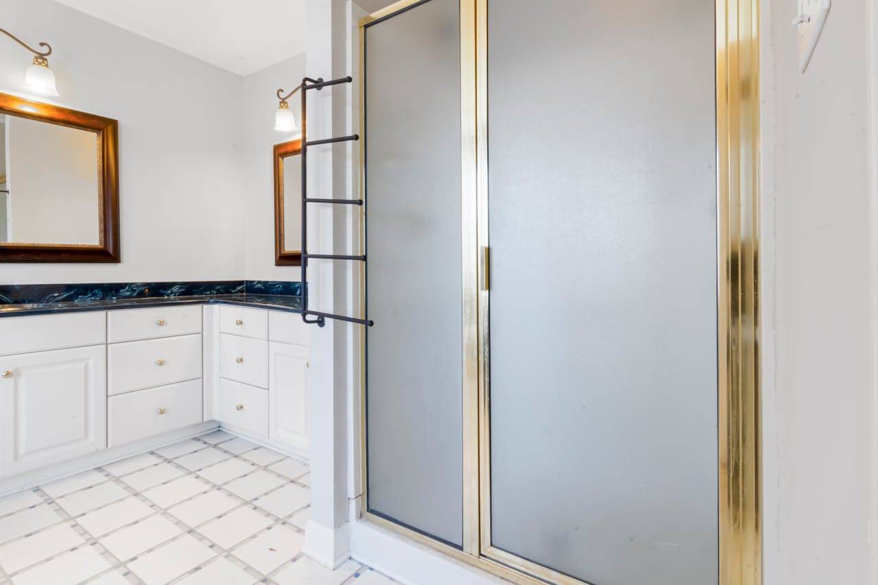 heros-img Elegant bathroom featuring a shower with gold trim and marble countertops, highlighting modern interior design.