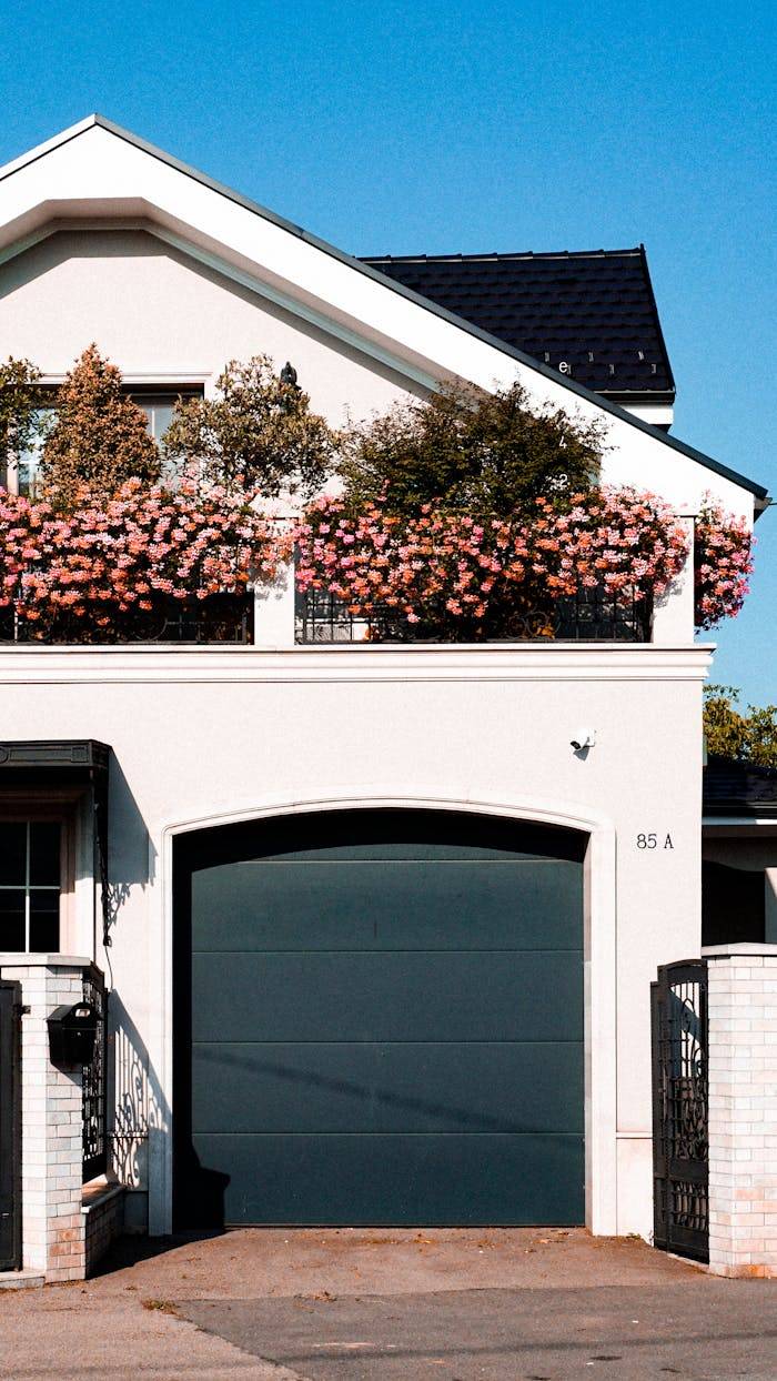 Stylish urban house in Cluj-Napoca featuring a garage and flowering balcony under a clear blue sky.