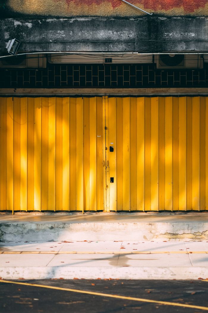 Bright yellow garage door in Klang, Malaysia, with urban texture and contrast.