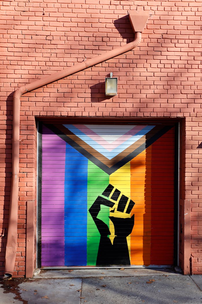 Colorful street art on a garage door with a raised fist and Progress Pride Flag in Sacramento.