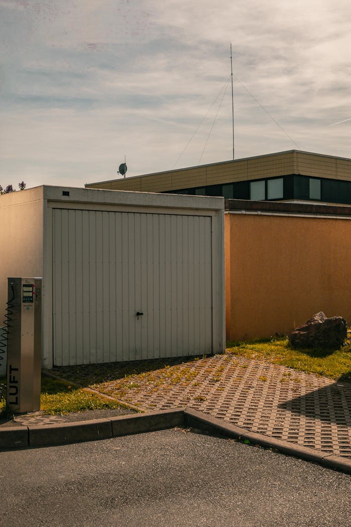 A minimalist urban scene featuring a closed garage, paving stones, and clean lines under a sunny sky.