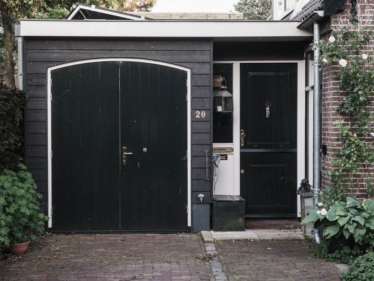 services-img Exterior of a traditional Dutch house with black doors and a landscaped garden.