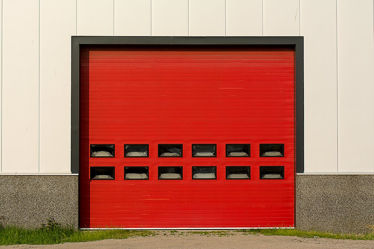 Bright red roller shutter garage door on industrial building exterior.